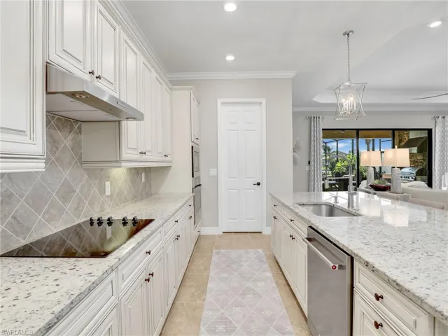 Kitchen featuring black electric cooktop, dishwasher, white cabinets, and decorative light fixtures