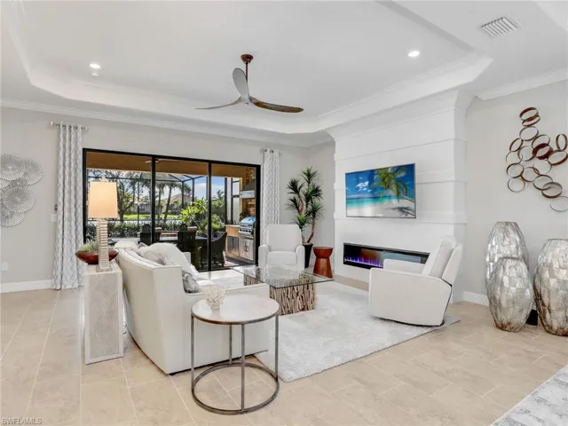 Living room featuring crown molding, a tray ceiling, and ceiling fan