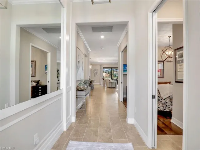 Corridor featuring ornamental molding, an inviting chandelier, and light tile patterned floors