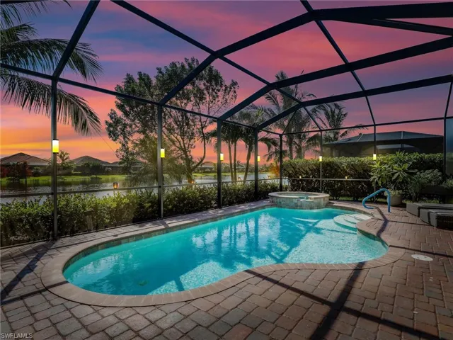 Pool at dusk featuring a patio, an in ground hot tub, a water view, and screened enclosure