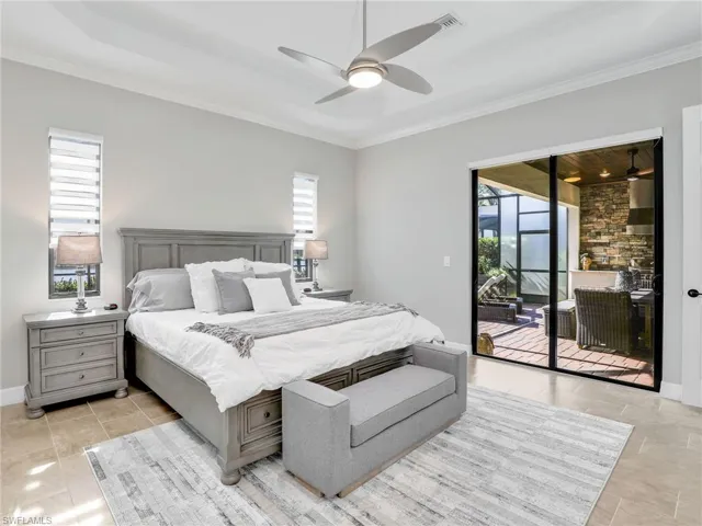 Tiled bedroom featuring multiple windows, ornamental molding, access to exterior, and ceiling fan