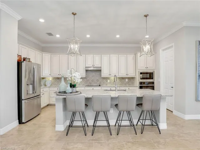 Kitchen featuring sink, a kitchen island with sink, stainless steel appliances, and white cabinetry