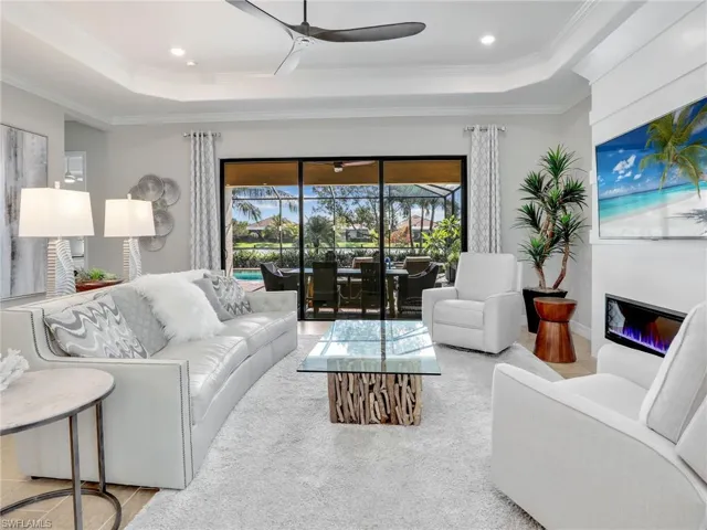 Living room featuring ornamental molding, ceiling fan, and a raised ceiling