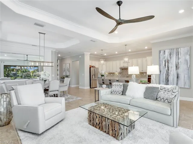 Tiled living room featuring ornamental molding, a tray ceiling, and ceiling fan
