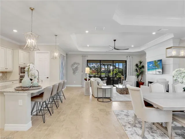 Dining area with ornamental molding, light tile patterned floors, and a raised ceiling
