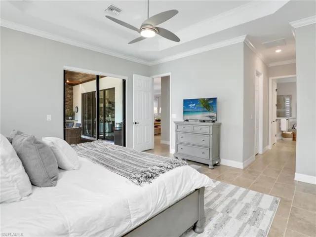 Tiled bedroom with ornamental molding, access to outside, and ceiling fan