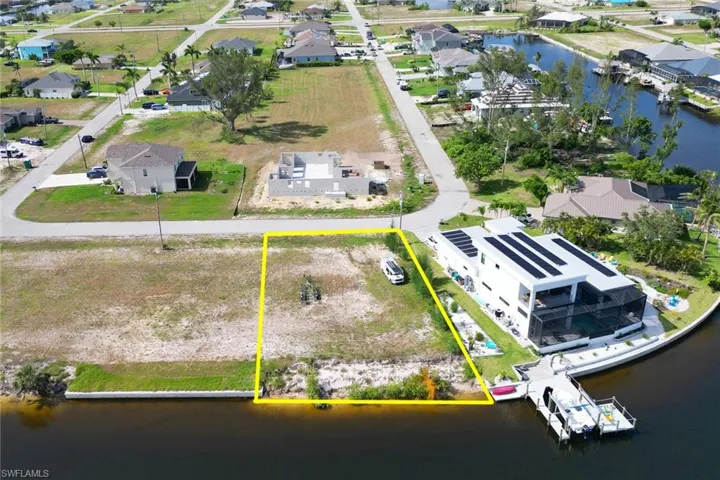 Aerial perspective of suburban area with property parcel outlined and a large body of water