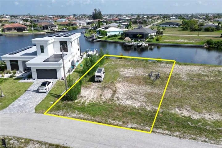 Aerial view of residential area featuring property parcel outlined and a nearby body of water