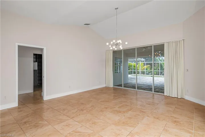 Empty room featuring a chandelier and high vaulted ceiling