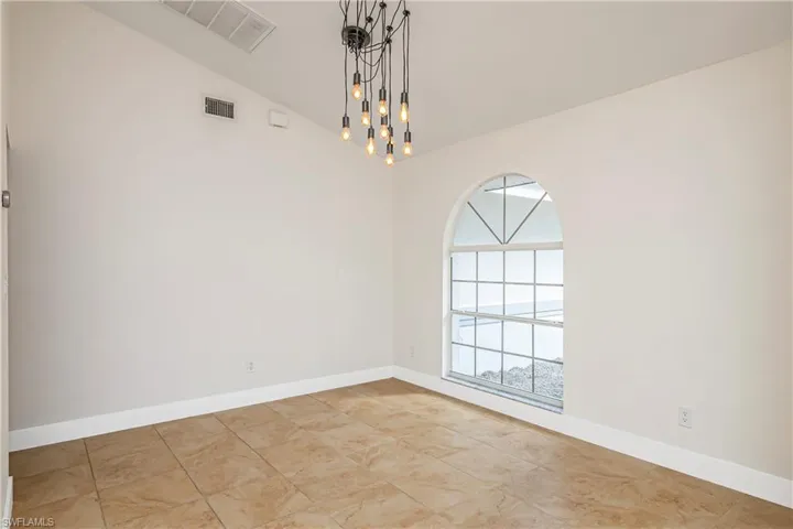 Empty room with vaulted ceiling and baseboards