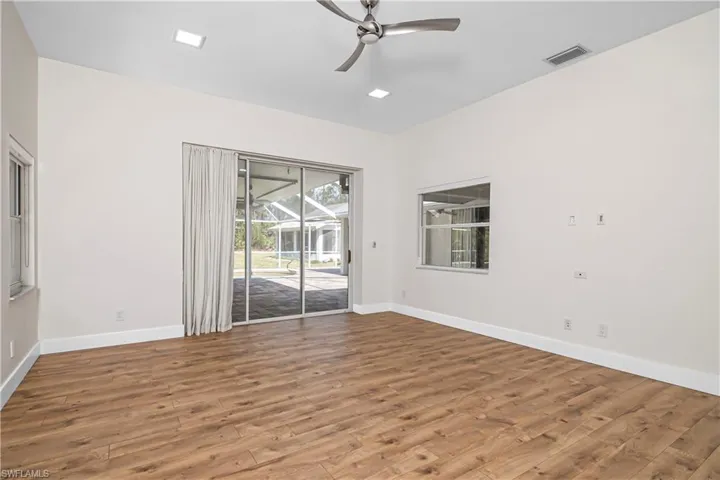 Empty room featuring ceiling fan, light wood-type flooring, and a sunroom