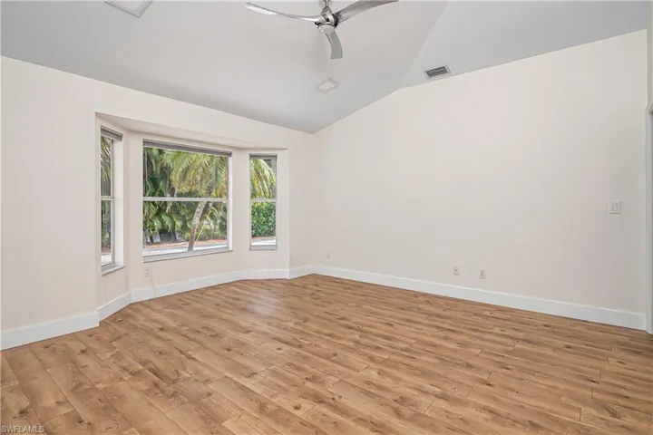 Spare room featuring a ceiling fan, light wood finished floors, and vaulted ceiling