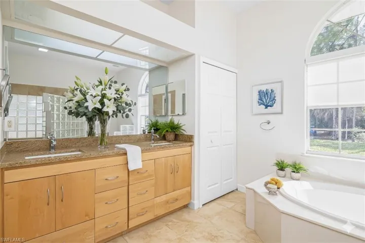 Bathroom featuring double vanity, a closet, and a bath