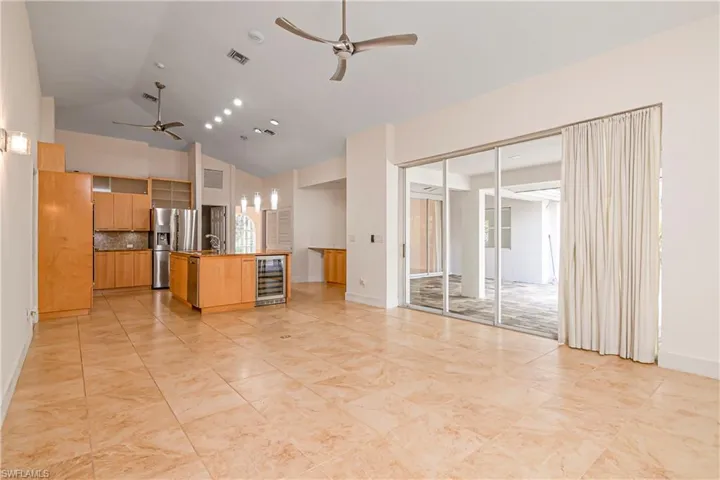 Unfurnished living room with ceiling fan, beverage cooler, and high vaulted ceiling