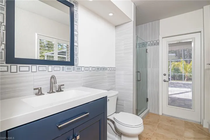 Bathroom featuring vanity, a stall shower, light tile patterned floors, and tile walls