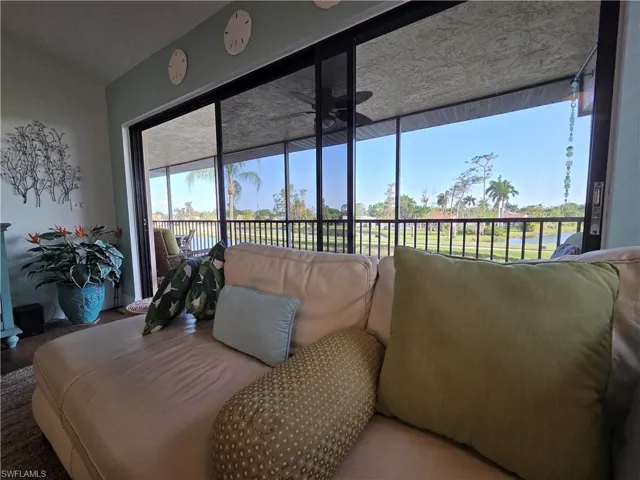 Living area featuring sliding glass doors that open to a screened lanai, offering expansive views of a body of water and distant trees