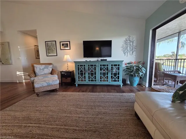 Spacious interior featuring hardwood floors, high ceilings, and direct access to a screened-in lanai with views of a body of water
