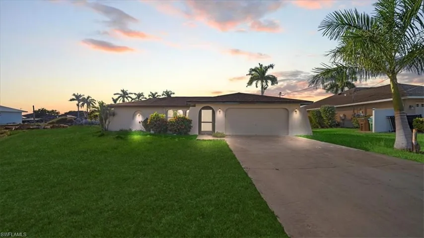 Ranch-style house with stucco siding, driveway, a yard, and a garage
