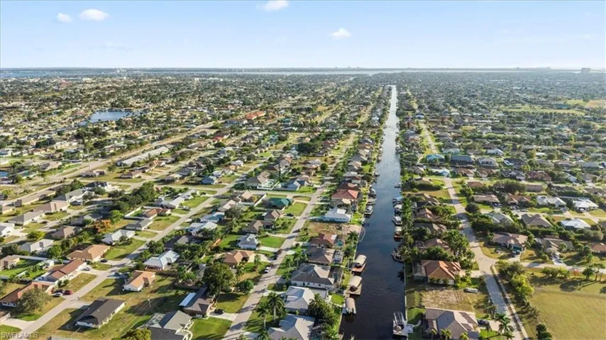 Aerial view of property and surrounding area featuring a large body of water and nearby suburban area