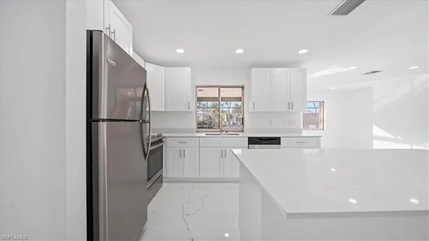 Kitchen featuring light marble finish floors, stainless steel appliances, recessed lighting, white cabinets, and light stone countertops