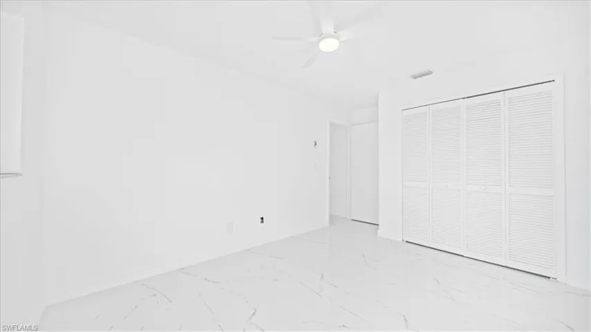 Unfurnished bedroom with ceiling fan, a closet, and light marble finish flooring