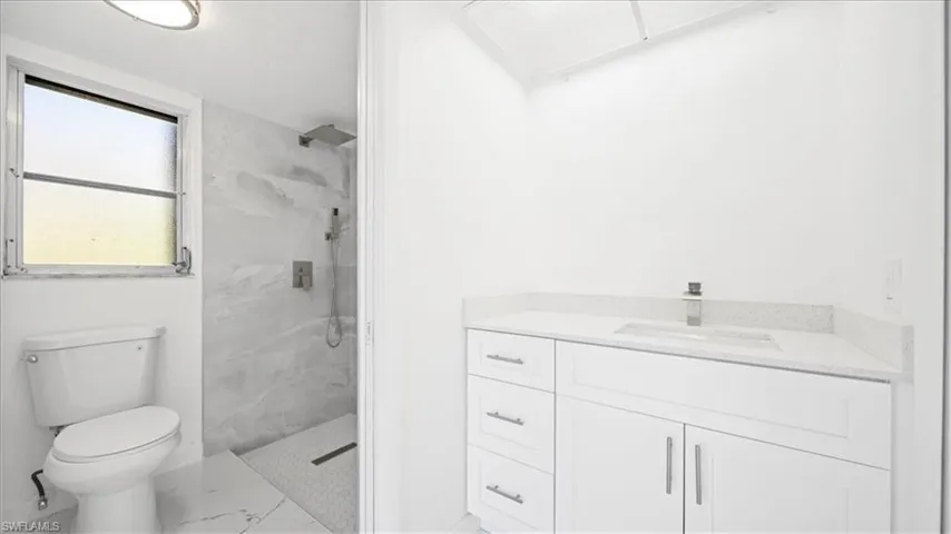 Bathroom with vanity and a marble finish shower