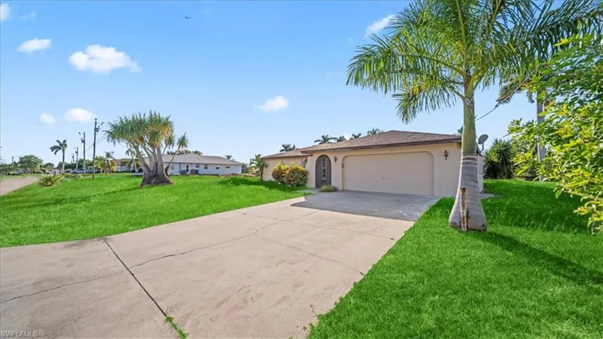 Single story home with a front yard, stucco siding, concrete driveway, and a garage