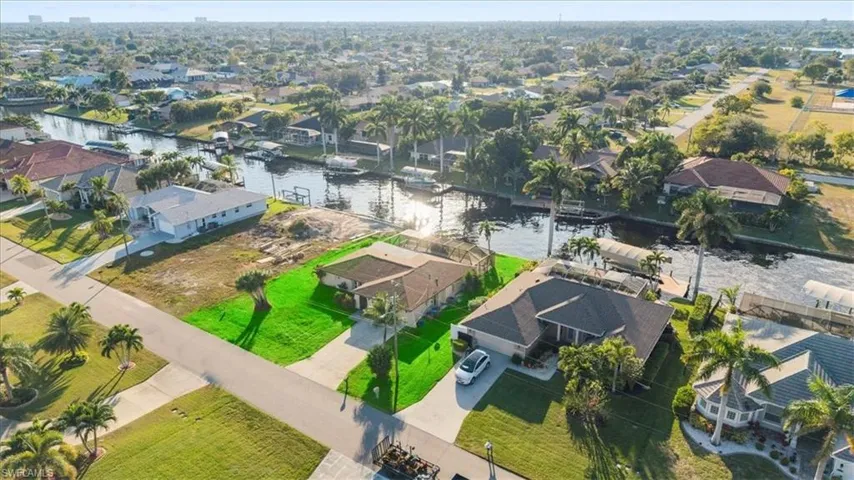 Aerial view of property and surrounding area featuring nearby suburban area and a nearby body of water