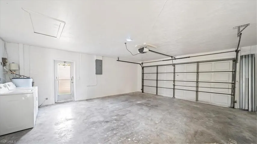 Garage featuring electric panel, washing machine and dryer, and a garage door opener