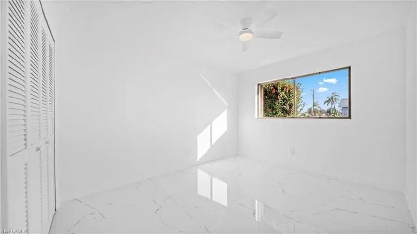 Unfurnished bedroom with marble finish flooring and ceiling fan