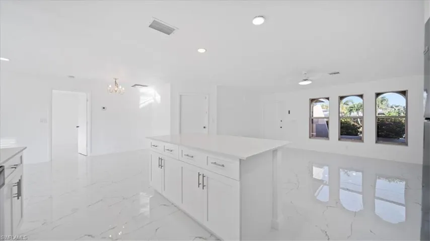Kitchen with recessed lighting, open floor plan, a center island, white cabinets, and light marble finish floors