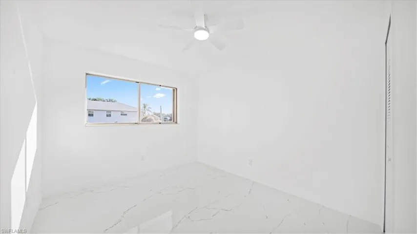 Empty room with marble finish floors and ceiling fan