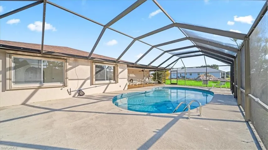 Outdoor pool with a sunroom, a patio area, glass enclosure, and a ceiling fan
