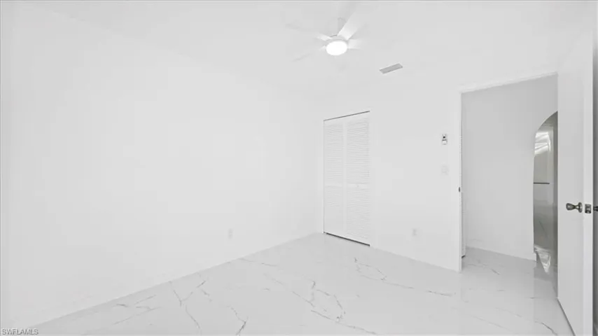 Unfurnished bedroom with a closet, light marble finish flooring, and a ceiling fan