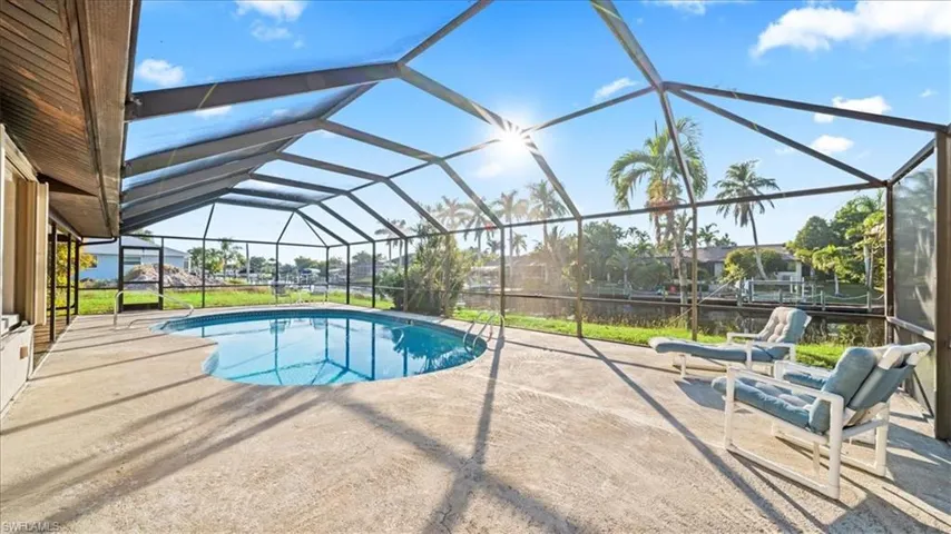 Swimming pool featuring a sunroom, glass enclosure, and a patio area