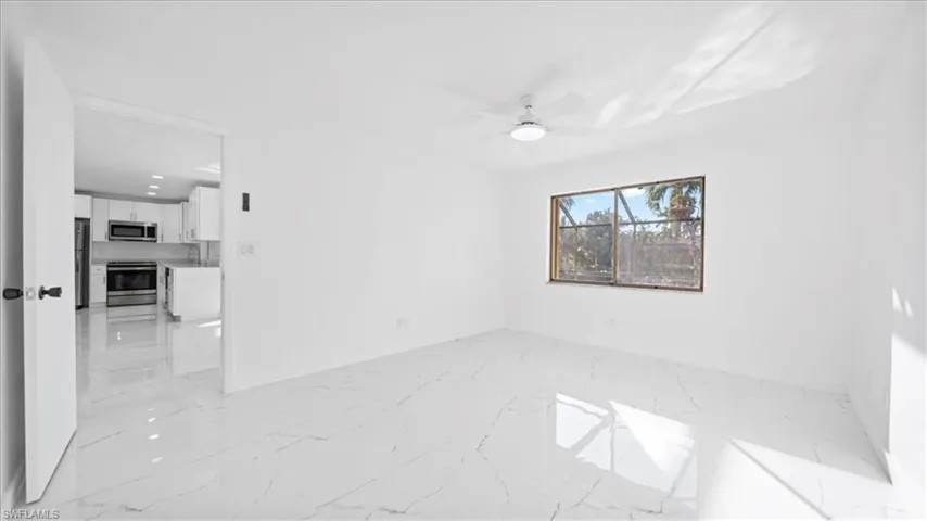 Unfurnished room featuring light marble finish flooring and ceiling fan