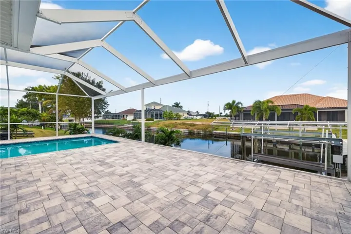 Swimming pool featuring glass enclosure, a sunroom, boat lift, a patio, and a water view