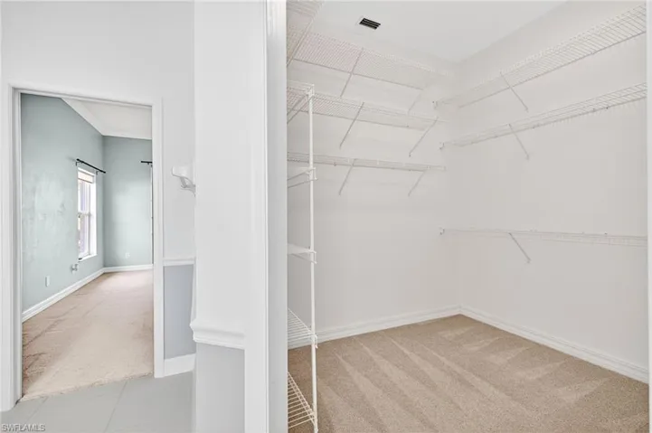 Walk in closet with light colored carpet and light tile patterned floors