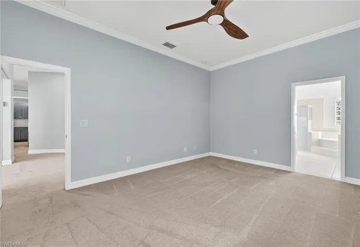 Unfurnished bedroom with light carpet, ornamental molding, ceiling fan, and connected bathroom