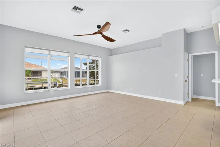 Empty room with light tile patterned floors and ceiling fan