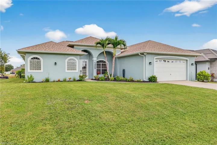 Mediterranean / spanish-style house with an attached garage, a front lawn, stucco siding, and driveway