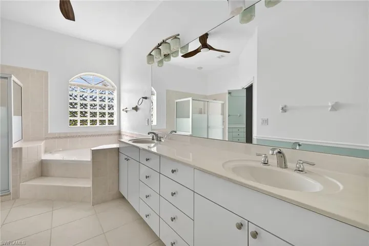 Bathroom with a stall shower, double vanity, a bath, light tile patterned floors, and ceiling fan