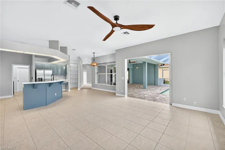 Unfurnished living room with ceiling fan, light tile patterned floors, and arched walkways