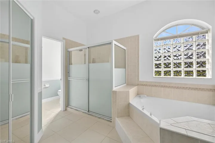 Bathroom with a shower stall, a bath, and light tile patterned flooring