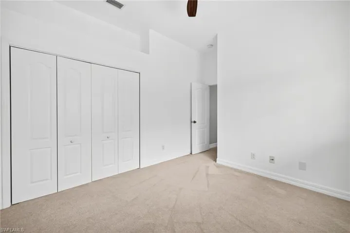 Unfurnished bedroom with carpet floors, a closet, ceiling fan, and a high ceiling