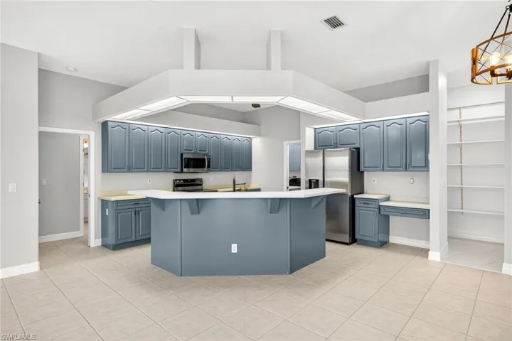 Kitchen with light countertops, a kitchen bar, a kitchen island with sink, light tile patterned flooring, and stainless steel appliances