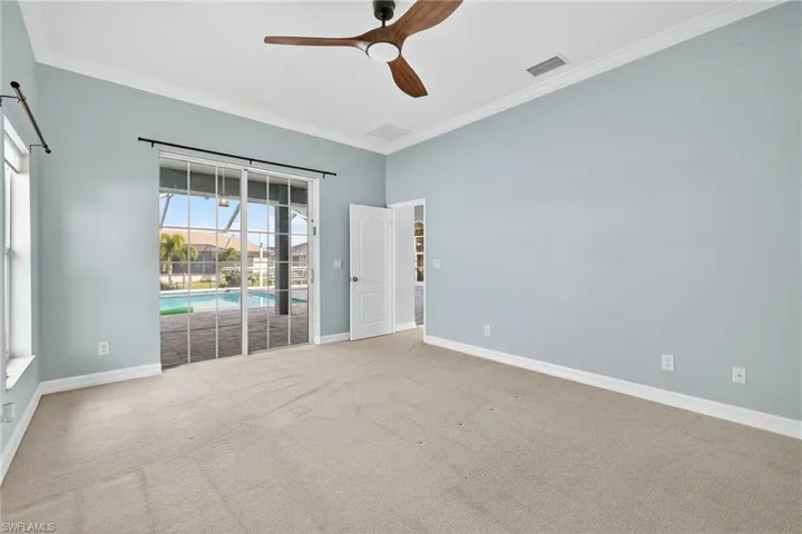 Empty room with ornamental molding, ceiling fan, a sunroom, and carpet