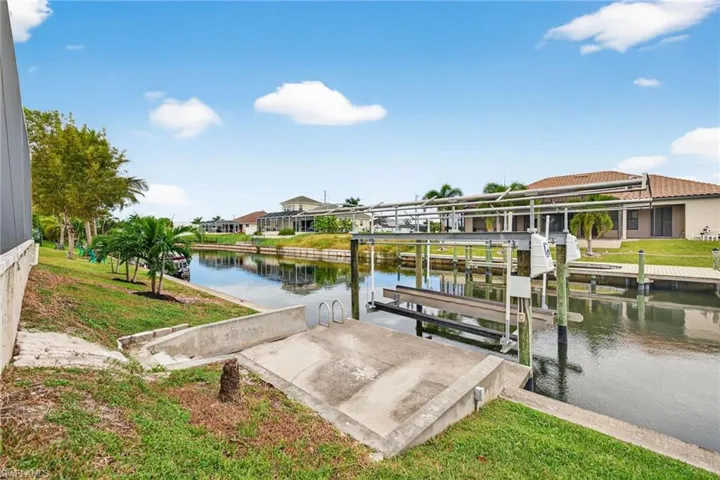 Dock area with boat lift, a lawn, a water view, and a residential view