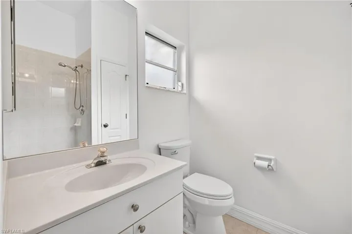 Full bath with vanity, tiled shower, and light tile patterned flooring