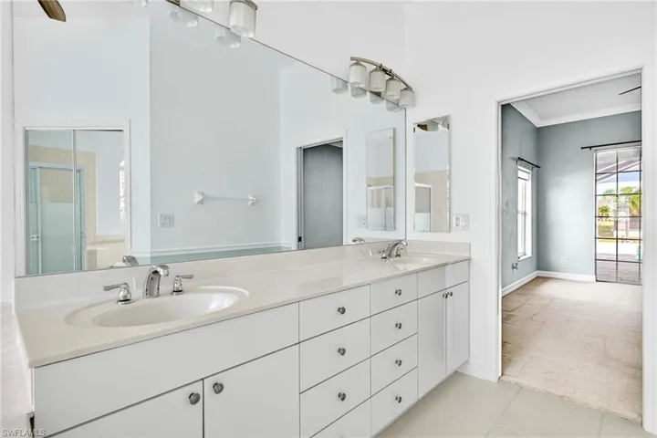 Bathroom with light colored carpet, double vanity, light tile patterned floors, a shower stall, and crown molding